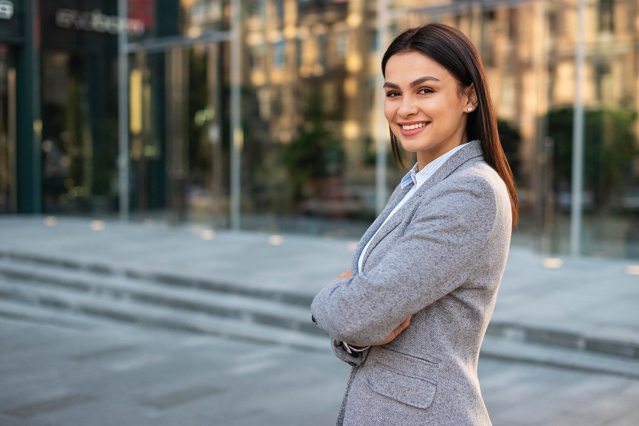 Strategische Nachfolgeplanung Businessfrau mit verschränkten Armen lächelt in Kamera